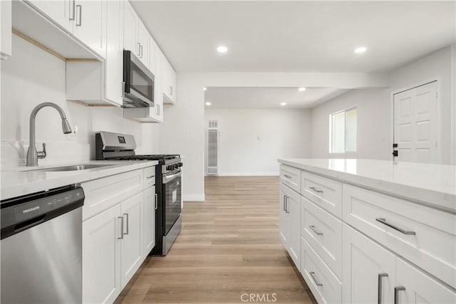 1151 Grand Ave, Colton, CA 92324 - kitchen with appliances with stainless steel finishes, white cabinets, light wood finished floors, recessed lighting, and light stone countertops