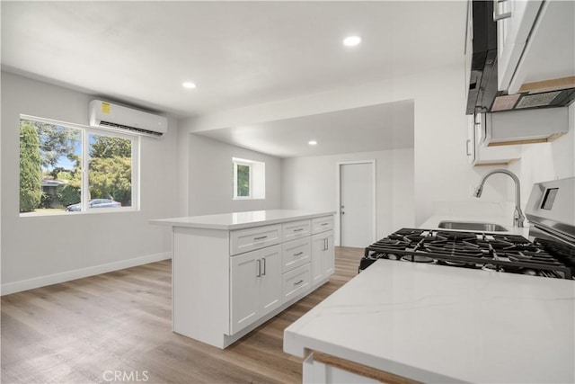 1151 Grand Ave, Colton, CA 92324 - kitchen with an AC wall unit, exhaust hood, light wood-style floors, white cabinets, and healthy amount of natural light