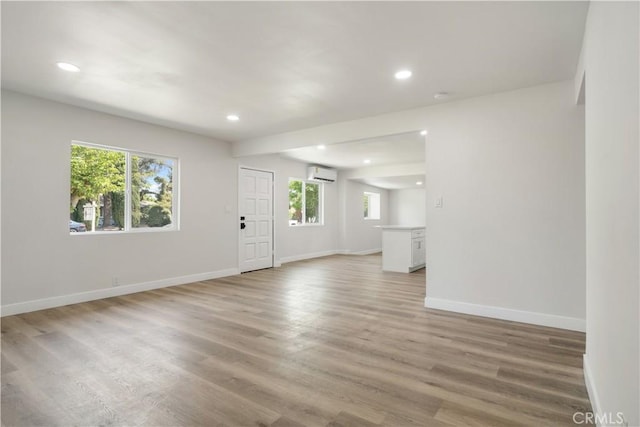 1151 Grand Ave, Colton, CA 92324 - unfurnished living room with a wall mounted AC, plenty of natural light, recessed lighting, and light wood finished floors