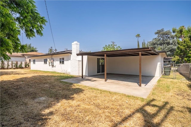 1151 Grand Ave, Colton, CA 92324 - rear view of house featuring a carport, a patio area, stucco siding, a chimney, and driveway