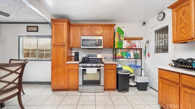 3510 E 2nd St, Los Angeles, CA 90063 - kitchen with stainless steel appliances, light countertops, brown cabinetry, and light tile patterned floors