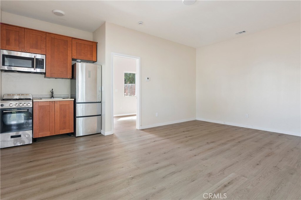 8856 Fullbright Ave, Winnetka, CA 91306 - kitchen with stainless steel appliances, a sink, light wood finished floors, and brown cabinetry