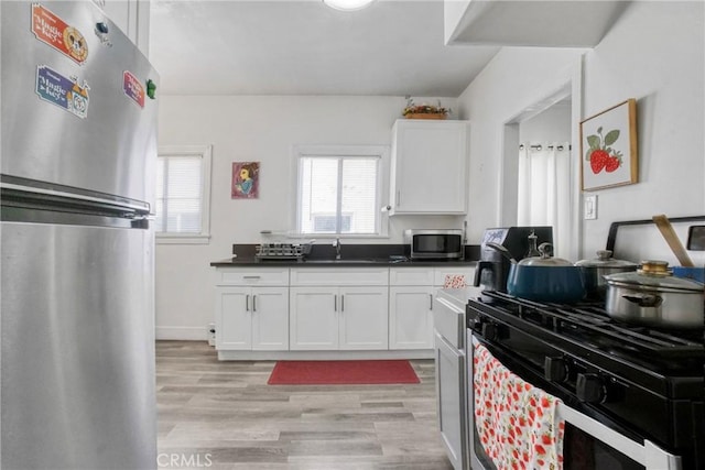 1732 W 48th St, Los Angeles, CA 90062 - kitchen with appliances with stainless steel finishes, a sink, light wood finished floors, and white cabinetry