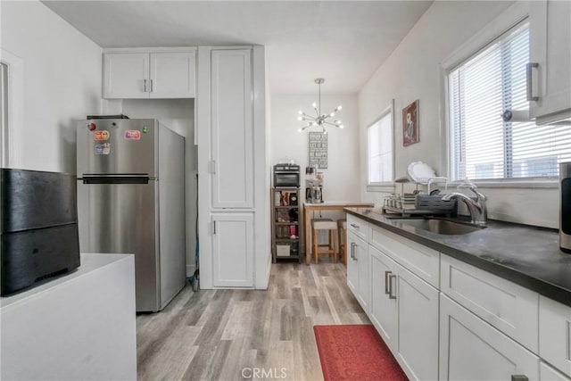 1732 W 48th St, Los Angeles, CA 90062 - kitchen featuring freestanding refrigerator, a sink, light wood-style floors, white cabinets, and dark countertops