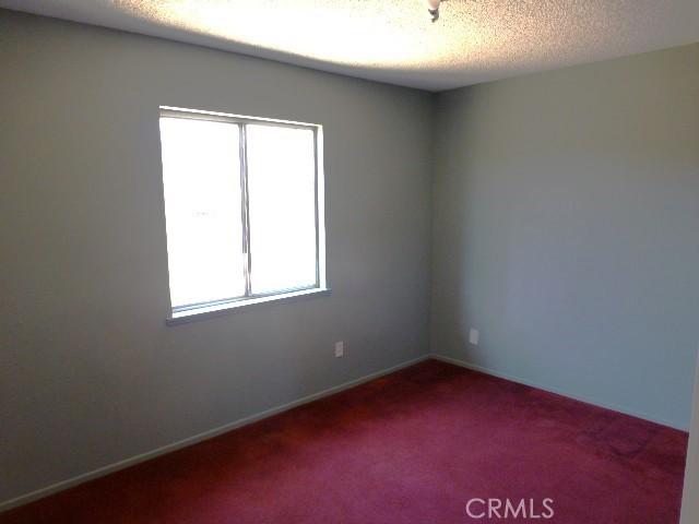 6070 Baileya Ave Unit 29, Palms, CA 92277 - carpeted empty room featuring plenty of natural light, a textured ceiling, and baseboards