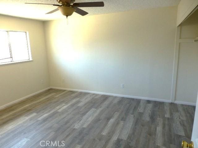 6070 Baileya Ave Unit 29, Palms, CA 92277 - unfurnished bedroom with wood finished floors, baseboards, ceiling fan, a closet, and a textured ceiling