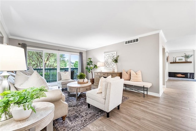 564 N Bellflower Blvd Unit 120, Long Beach, CA 90814 - living area featuring crown molding, light wood-style flooring, and a warm lit fireplace