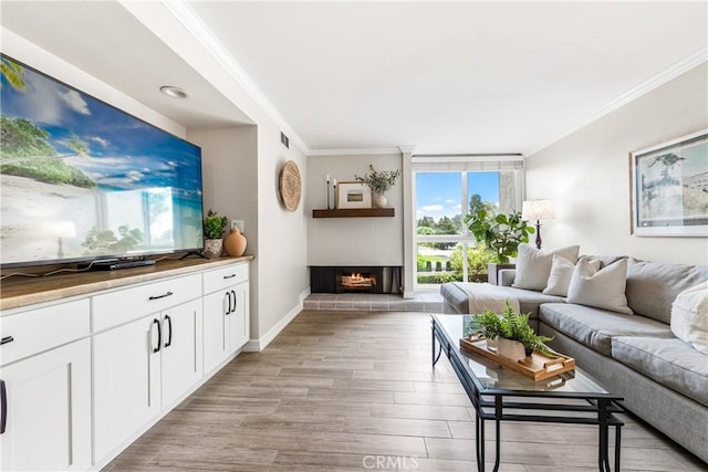 564 N Bellflower Blvd Unit 120, Long Beach, CA 90814 - living room with crown molding, light wood-style flooring, a warm lit fireplace, and baseboards