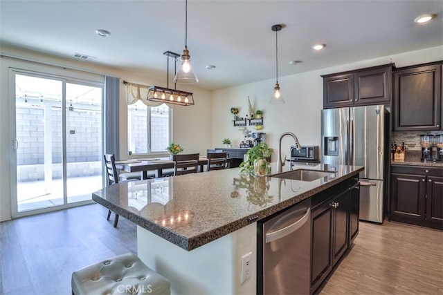 6886 Cache Way, Jurupa Valley, CA 91752 - kitchen with appliances with stainless steel finishes, light wood-style floors, dark brown cabinetry, a breakfast bar, and recessed lighting
