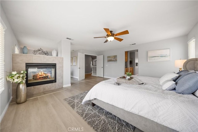 12337 Columbia Ln, Eastvale, CA 91752 - bedroom with light wood finished floors, a tiled fireplace, and ceiling fan