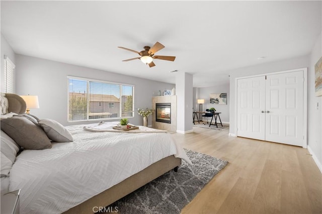 12337 Columbia Ln, Eastvale, CA 91752 - bedroom with light wood finished floors, a ceiling fan, and a tiled fireplace