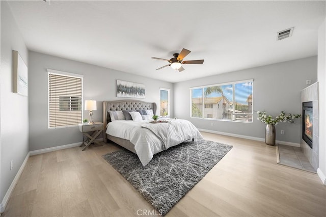 12337 Columbia Ln, Eastvale, CA 91752 - bedroom with light wood finished floors, a ceiling fan, and a glass covered fireplace