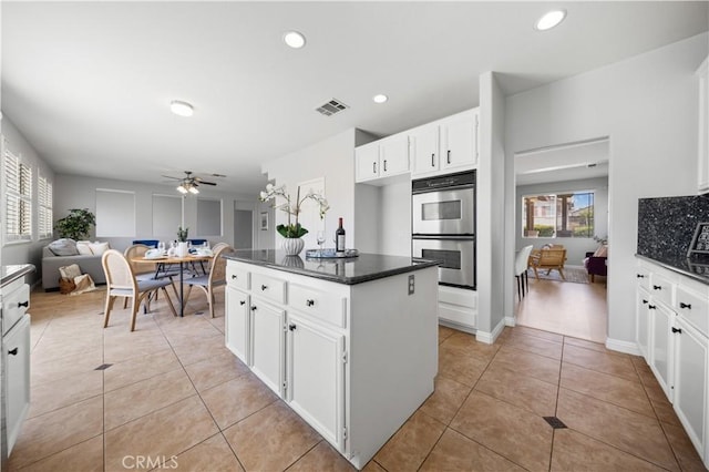 12337 Columbia Ln, Eastvale, CA 91752 - kitchen featuring double oven, ceiling fan, light tile patterned flooring, white cabinetry, and a center island