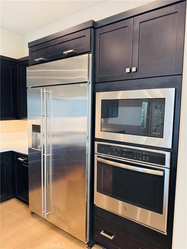 158 Scale, Irvine, CA 92618 - kitchen with built in appliances, light countertops, light wood-style floors, and dark cabinetry