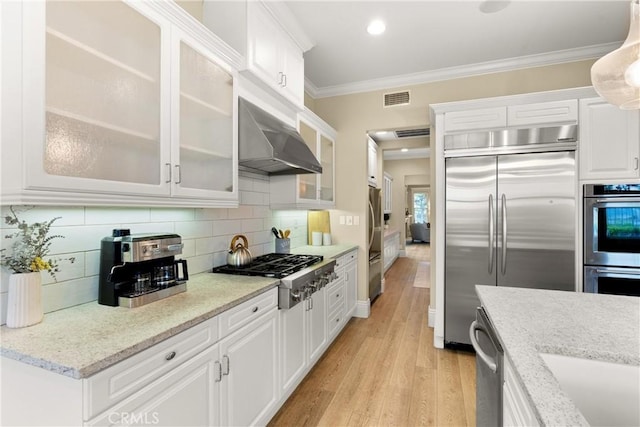 37 Craftsbury Pl, Ladera Ranch, CA 92694 - kitchen featuring stainless steel appliances, wall chimney range hood, crown molding, white cabinets, and light wood finished floors