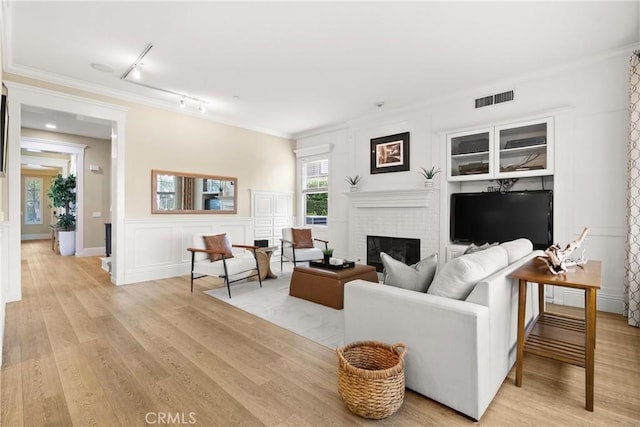 37 Craftsbury Pl, Ladera Ranch, CA 92694 - living room with rail lighting, light wood-type flooring, a fireplace, a decorative wall, and ornamental molding