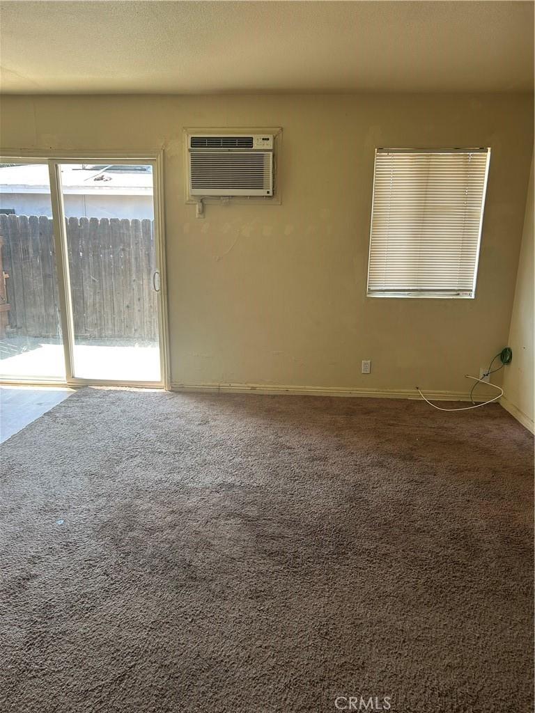 2121 Down St, Riverside, CA 92507 - carpeted empty room featuring a wall mounted AC and baseboards