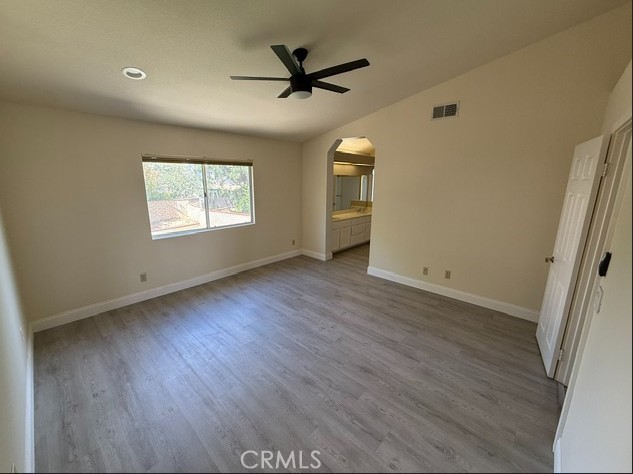 27745 Desert Pl, Castaic, CA 91384 - unfurnished bedroom featuring arched walkways, wood finished floors, lofted ceiling, ensuite bathroom, and ceiling fan