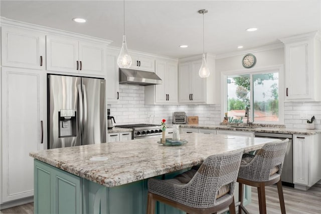 27705 Calle Valdes, Mission Viejo, CA 92692 - kitchen featuring appliances with stainless steel finishes, under cabinet range hood, white cabinets, a kitchen island, and ornamental molding