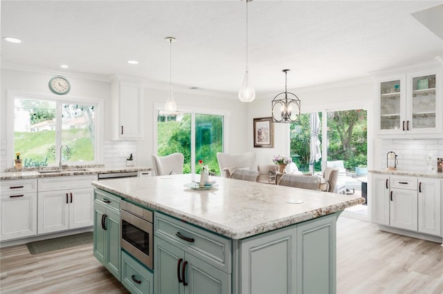 27705 Calle Valdes, Mission Viejo, CA 92692 - kitchen featuring stainless steel microwave, decorative backsplash, light wood-style floors, white cabinets, and light stone counters