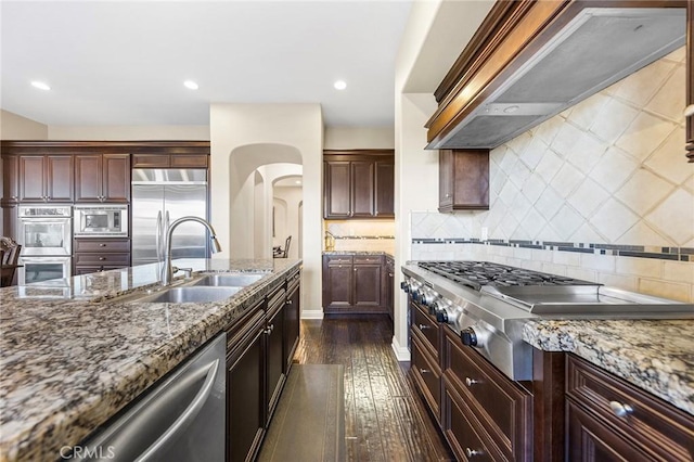 19599 Highland Terrace Dr, Walnut, CA 91789 - kitchen with wall chimney range hood, a sink, built in appliances, dark wood finished floors, and dark stone counters