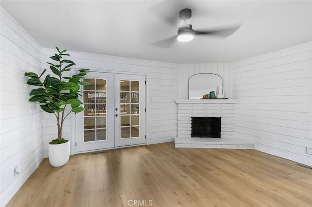 4561 N Price Ave, Fresno, CA 93726 - unfurnished living room featuring french doors, a ceiling fan, wood finished floors, a brick fireplace, and wooden walls