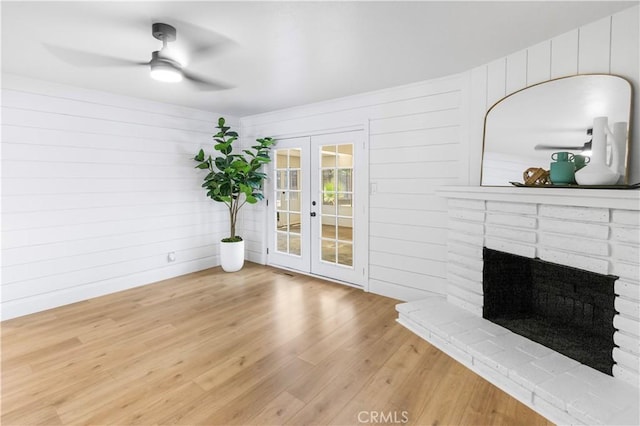 4561 N Price Ave, Fresno, CA 93726 - unfurnished living room with french doors, ceiling fan, wood finished floors, a fireplace, and wooden walls