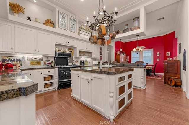 8401 Mayer Ave, Bakersfield, CA 93314 - kitchen featuring open shelves, a chandelier, white cabinetry, wood finished floors, and ornamental molding