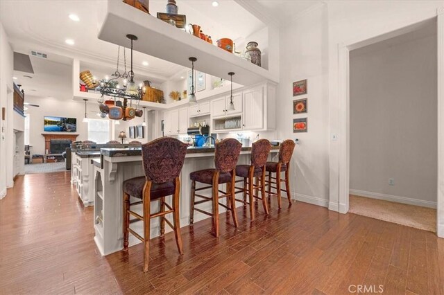8401 Mayer Ave, Bakersfield, CA 93314 - kitchen featuring white cabinets, wood finished floors, a peninsula, baseboards, and a kitchen bar