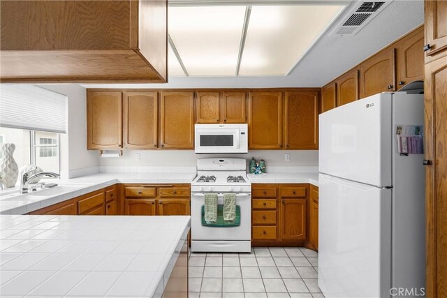 2300 Maple Ave Unit 138, Torrance, CA 90503 - kitchen with white appliances, tile countertops, a sink, and brown cabinetry