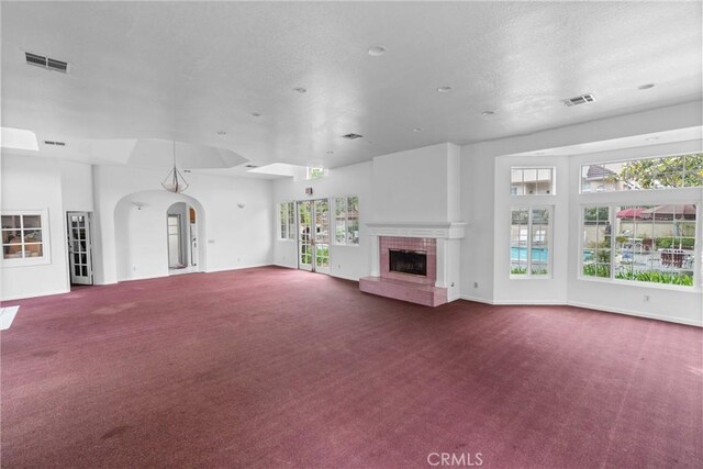 2300 Maple Ave Unit 138, Torrance, CA 90503 - unfurnished living room featuring carpet flooring, a fireplace with raised hearth, a textured ceiling, and arched walkways