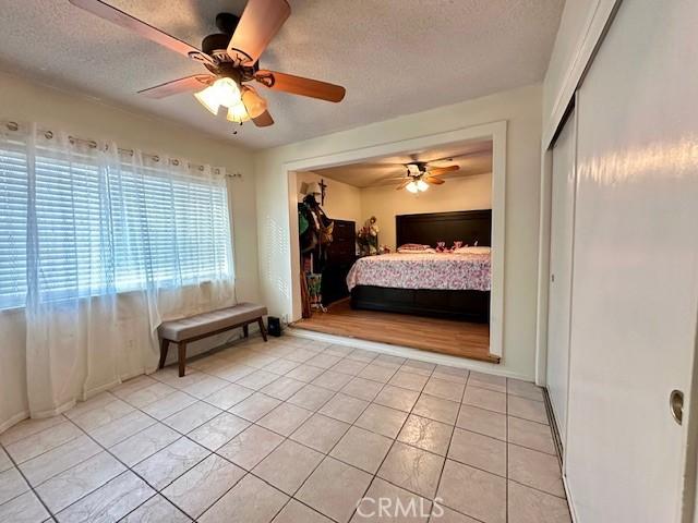27441 Villa Ave, Highland, CA 92346 - bedroom featuring light tile patterned flooring, a textured ceiling, ceiling fan, and a closet