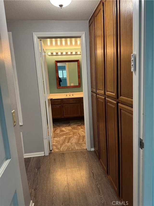 19029 Nordhoff St Unit 309, Northridge, CA 91324 - corridor featuring wood finished floors, a sink, baseboards, and a textured ceiling