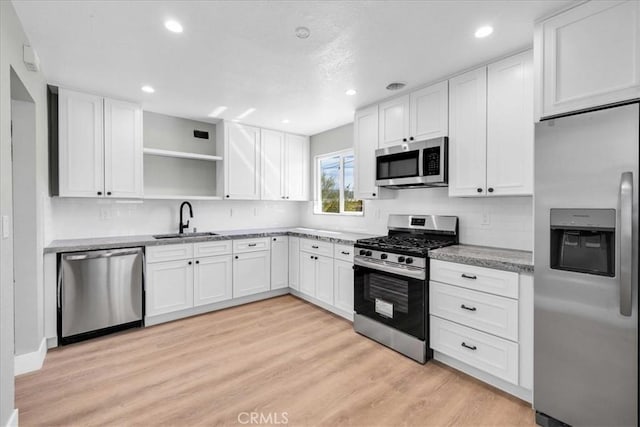 73461 El Paseo Dr Unit 29, Palms, CA 92277 - kitchen with stainless steel appliances, white cabinets, open shelves, light wood finished floors, and recessed lighting