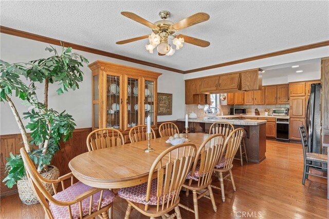 524 Golf Course Rd, Lake Arrowhead, CA 92352 - dining room with a textured ceiling, wainscoting, light wood-style floors, a ceiling fan, and crown molding