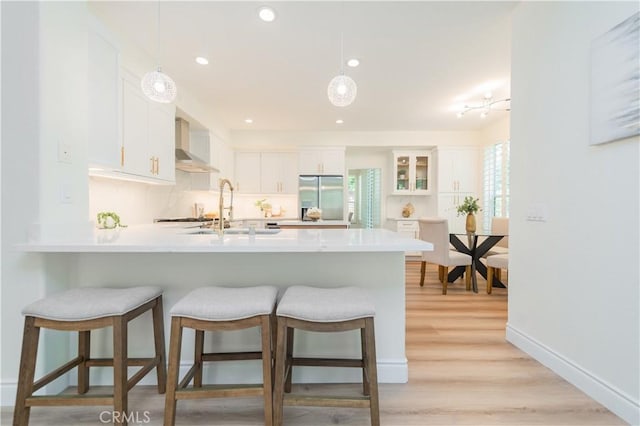 2115 Via Viejo, San Clemente, CA 92673 - kitchen with stainless steel refrigerator with ice dispenser, wall chimney exhaust hood, a peninsula, white cabinetry, and recessed lighting