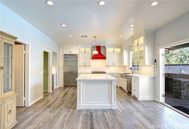 19068 Sunflower Pl, Riverside, CA 92508 - kitchen featuring stainless steel appliances, wall chimney range hood, light countertops, light wood-type flooring, and a kitchen island