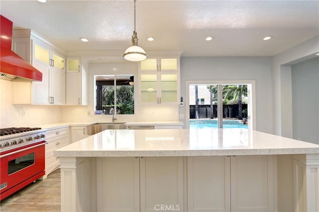 19068 Sunflower Pl, Riverside, CA 92508 - kitchen featuring premium stove, wall chimney range hood, white cabinets, light wood-type flooring, and recessed lighting