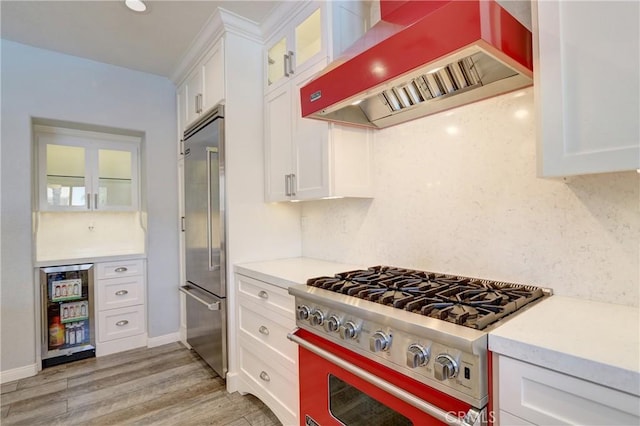 19068 Sunflower Pl, Riverside, CA 92508 - kitchen with high end appliances, wall chimney exhaust hood, white cabinetry, light countertops, and light wood-style floors