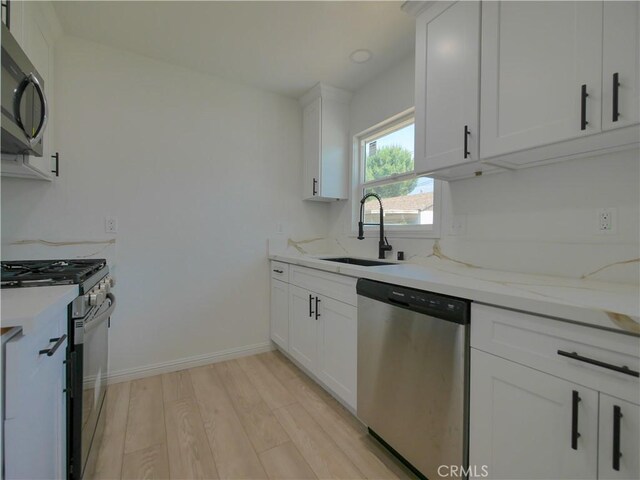 24931 Vine St, San Bernardino, CA 92410 - kitchen featuring appliances with stainless steel finishes, light wood-style flooring, white cabinetry, and light stone countertops