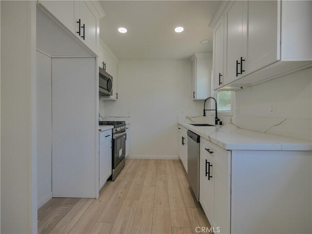 24931 Vine St, San Bernardino, CA 92410 - kitchen with appliances with stainless steel finishes, light wood-style flooring, light stone countertops, white cabinetry, and recessed lighting