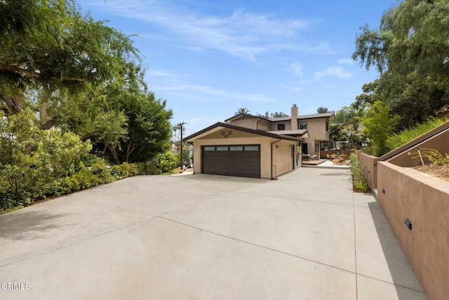 845 Rollin St, South Pasadena, CA 91030 - view of side of home with concrete driveway, an attached garage, stucco siding, and a chimney
