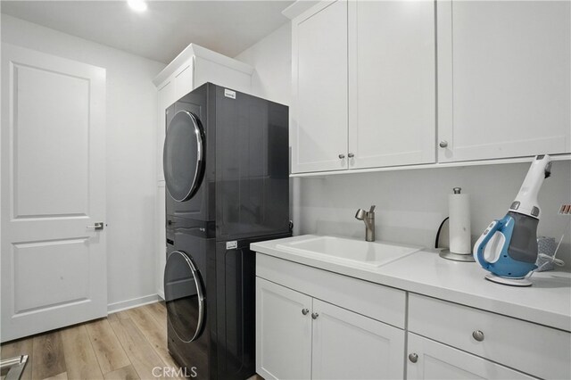 28410 Orange Park Dr, Castaic, CA 91384 - laundry area with stacked washing machine and dryer, cabinet space, and light wood-type flooring
