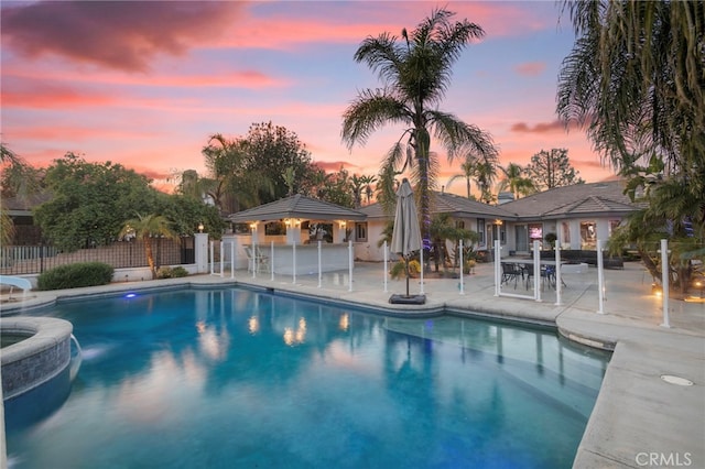 1042 Coronet Dr, Riverside, CA 92506 - pool at dusk featuring a patio area, a gazebo, and a pool with connected hot tub
