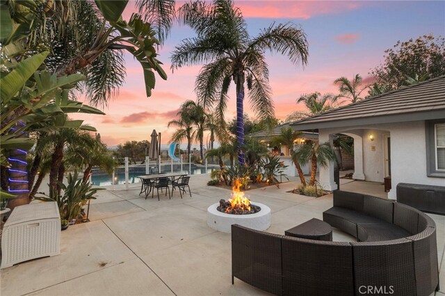 1042 Coronet Dr, Riverside, CA 92506 - patio terrace at dusk with a pool, a patio area, and an outdoor living space with a fire pit