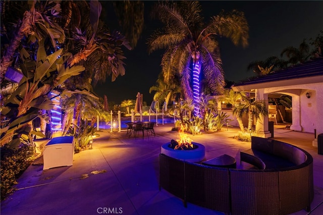 1042 Coronet Dr, Riverside, CA 92506 - patio at twilight featuring a fire pit, a patio, outdoor dining space, and a pool