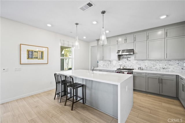 27774 Marquee Dr, Valencia, CA 91381 - kitchen with gray cabinetry, light wood-style flooring, backsplash, under cabinet range hood, and recessed lighting