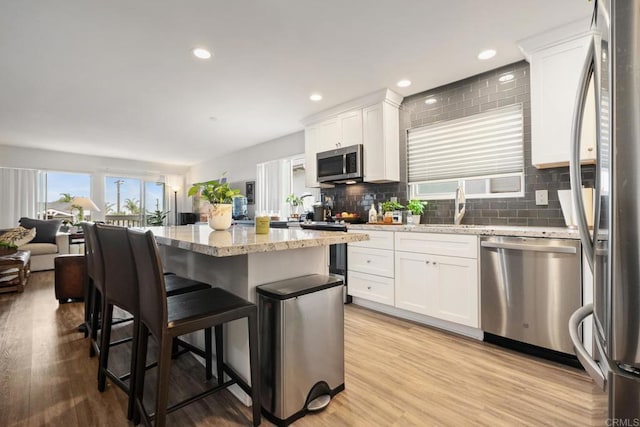 245355 Newcastle Ave, Cardiff By The Sea, CA 92007 - kitchen with appliances with stainless steel finishes, a kitchen bar, white cabinetry, light stone counters, and decorative backsplash