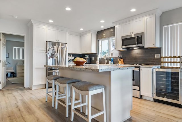 245355 Newcastle Ave, Cardiff By The Sea, CA 92007 - kitchen with wine cooler, appliances with stainless steel finishes, light wood-style flooring, white cabinets, and backsplash