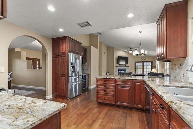 1896 Via Del Torrie, Alpine, CA 91901 - kitchen with appliances with stainless steel finishes, a peninsula, arched walkways, dark wood-style floors, and light stone countertops